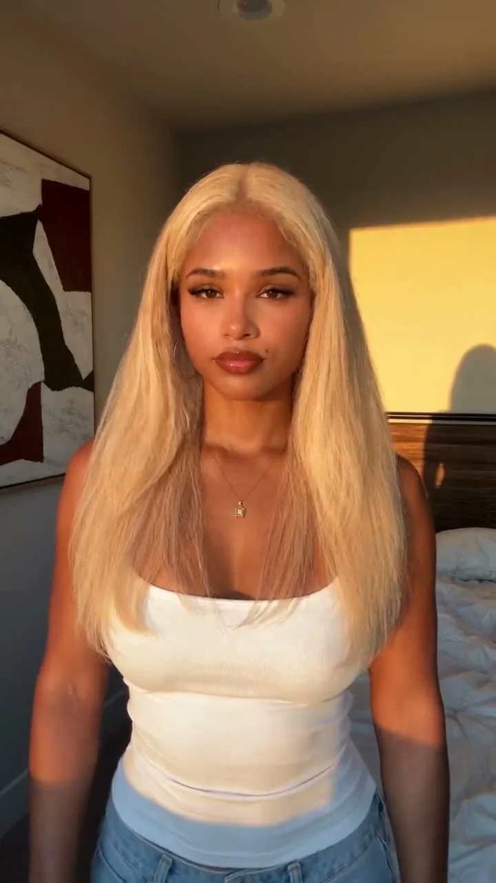 Front-facing portrait of a woman with long straight blonde hair in warm sunlight, before a bob-cut reveal