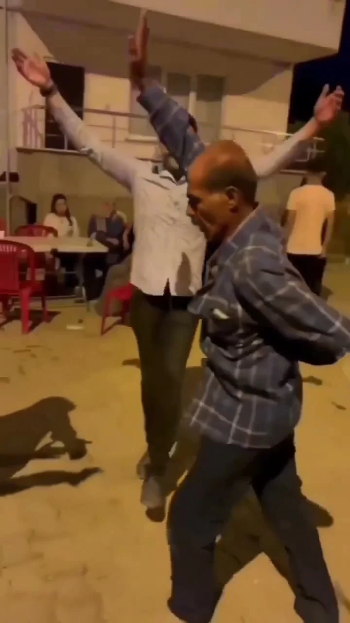 Dancer in a blue plaid shirt that hangs like a jacket at an outdoor wedding
