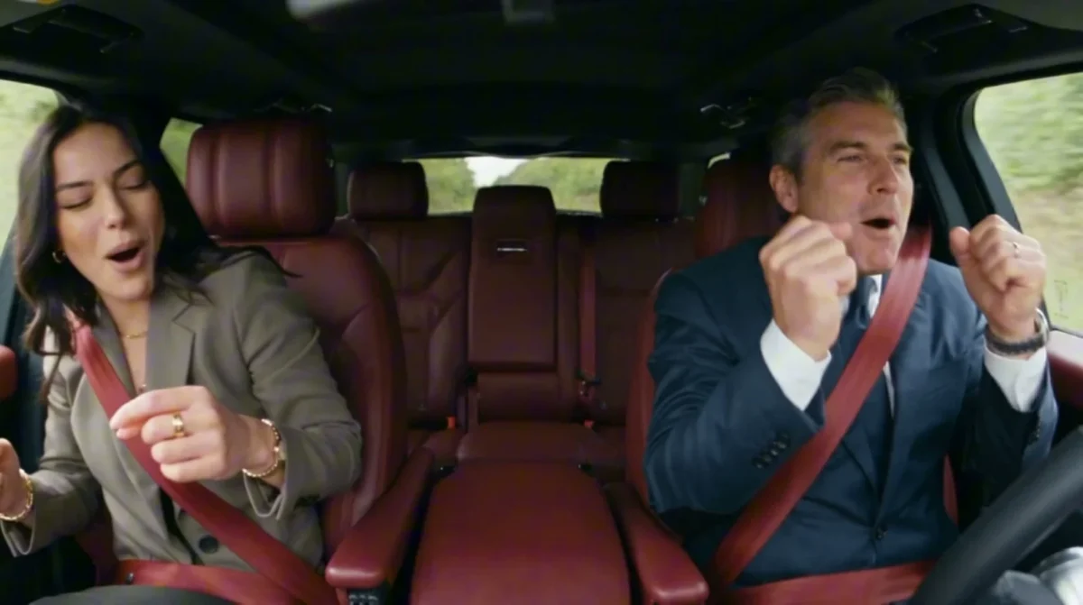 Two seat-belted performers dancing in the front seats of a car