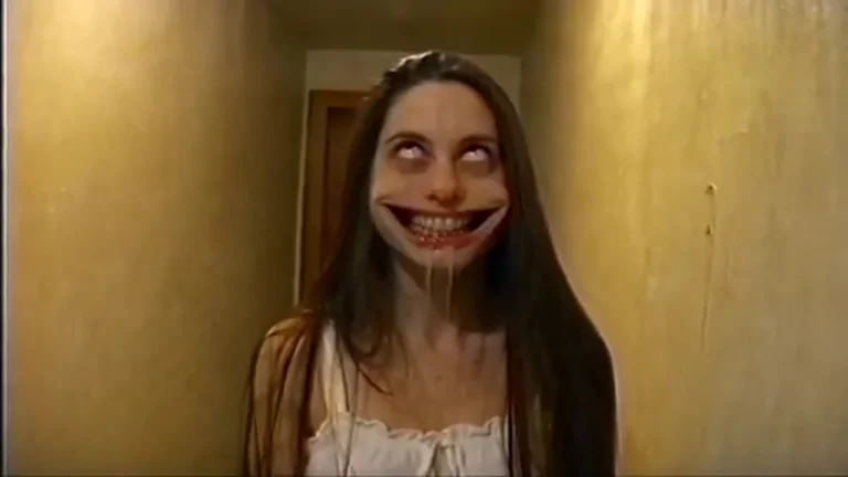 Source preview of a long-haired person in a white nightgown with rolled-back eyes and a stretched grin in a narrow yellow hallway