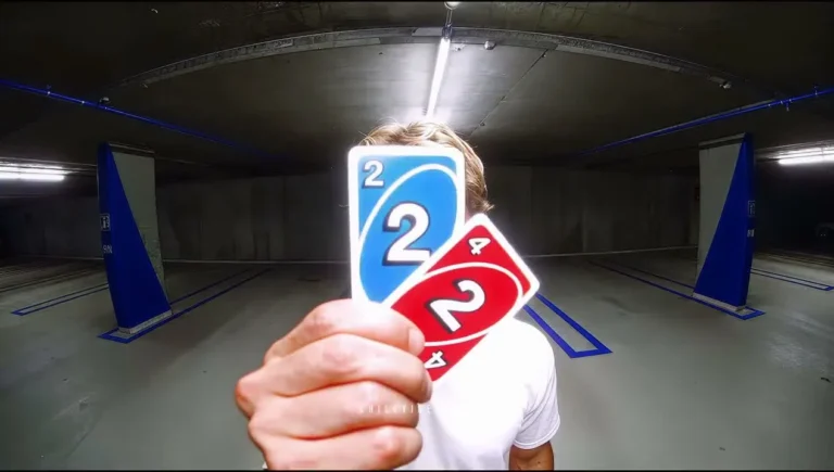 A person holding blue and red number cards close to the camera in a parking garage.